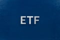 The abbreviation word etf - Exchange Traded Fund - laid with silver letters on blue color flat surface