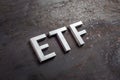 The abbreviation word etf - Exchange Traded Fund - laid with silver letters on raw rusted steel sheet surface in slanted