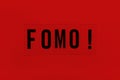 Abbreviation word FOMO on transparent plastic on red background. It means Fear Of Missing Out, non-stop internet surfing. Concept