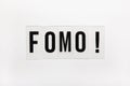 Abbreviation word FOMO on transparent plastic on white. It means Fear Of Missing Out, non-stop internet surfing. Concept social