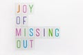 Abbreviation word JOMO, multicolored plastic letters on white background. JOMO - Joy Of Missing Out. Opposition, choice, social Royalty Free Stock Photo