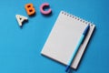 ABC-the first letters of the English alphabet on a blue background. Notebook and pen. Empty space for text. Learn foreign Royalty Free Stock Photo