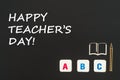 Abc letters and chipboard miniature on blackboard with text happy teacher`s day