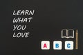 Abc letters and chipboard miniature on blackboard with text learn what you love Royalty Free Stock Photo