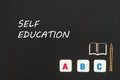 Abc letters and chipboard miniature on blackboard with text self education