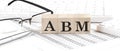 ABM text on a wooden block on chart background