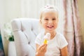Aborable smiling blonde 3 years baby girl eating homemade ice cream and laughing