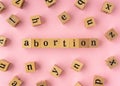 Abortion word on wooden block. Flat lay view on light pink background