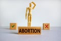 `Abortion` word written in wooden block. Wooden model of a man reflecting on a choice. Beautiful white background, copy space. Royalty Free Stock Photo