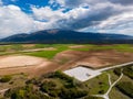 From above, the agricultural fields nestled amidst towering mountains in Greece create a stunning aerial view