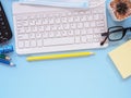 Above, close-up keyboard and medical face mask with office supplies, cactus on blue workplace table. Royalty Free Stock Photo