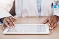 Above closeup african american woman doctor using a digital tablet while working at a desk in her hospital office. Using Royalty Free Stock Photo