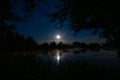 Above lake the stars and the moon can be seen in the night sky