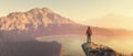 Hiker with a backpack on top of a rock admiring mountains view.