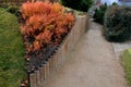 Above the ornamental pond in the park are several gray metal transparent benches on the park gravel sidewalk. autumn leaves lying