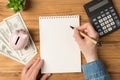 Above photo of notebook pen hands money earnings cash green plant moneybox and calculator isolated on the wooden backdrop Royalty Free Stock Photo