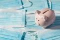 Above photo of piggybank pink pig with pile of blue masks on the background isolated