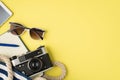 Above photo of sunglasses phone bag camera notebook and blue pen isolated on the yellow background with empty space