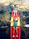 Above portrait of two diverse young women cheering and celebrating while canoeing on a lake. Excited friends enjoying