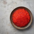 From above red fresh trout fish caviar served in a bowl on concrete table background