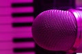 Above shot of condenser microphone with synthesizer keyboard for music production making. Purple light Royalty Free Stock Photo