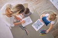 Above shot of little girl and boy sitting at table with colourful pencils and pictures while colouring with mom helping Royalty Free Stock Photo