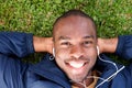 Above of smiling african american man lying on grass listening to music with earphones Royalty Free Stock Photo