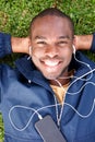 Above of smiling young black man lying on grass listening to music with earphones Royalty Free Stock Photo