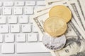 Above top overhead close up view photo of golden and silver crypto currency laying on paper american banknotes with white keyboard