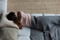 Exhausted latin woman sleep on couch in clothes under plaid