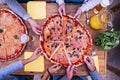 Above and top view of two big pizzas with a lot of hands taking a pieze of it - wooden table - dinner in family or friends Royalty Free Stock Photo