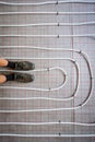 Worker stand on pipe system of floor heating mounted in residential building under construction Royalty Free Stock Photo