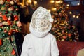 unrecognizable child in white shirt and santa hat stands on christmas tree background. Christmas celebration and fun