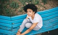 Above view of beautiful pensive African American woman sitting on bench outdoors in the park. Pretty dark-skinned female sitting Royalty Free Stock Photo