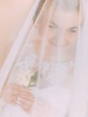 The above view of the bride holding the white mini-bouquet under the veil.