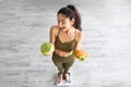 Above view of cheerful Indian lady holding cabbage and hamburger on scales indoors, full length