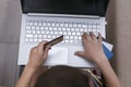 Above view of child with credit card in his hand pressing buttons on keyboard of laptop, Royalty Free Stock Photo