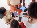 Above view of diverse group of unknown ambitious businesswomen huddled together and using technology in middle. Ethnic