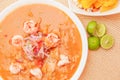 Above view of Ecuadorian food: shrimp cebiche with some chifles inside white bowl, lemon in a wooden table background