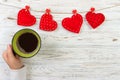 Above view of female hand holding hot cup of coffee with red heart on wood table. Photo in vintage color image style Royalty Free Stock Photo