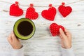 Above view of female hand holding hot cup of coffee with red heart on wood table. Photo in vintage color image style Royalty Free Stock Photo