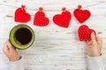 Above view of female hand holding hot cup of coffee with red heart on wood table. Photo in vintage color image style Royalty Free Stock Photo