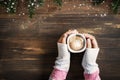 Above view of female hand holding hot cup of coffee on wood table. Royalty Free Stock Photo