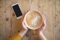 Above view of female hands holding hot cup of coffee and with smart phone Royalty Free Stock Photo