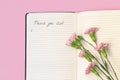 Above view of flowers on open paper notepad with handwritten words Thank you list. Gratitude journal