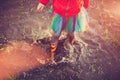 Crop girl playing in muddy puddle