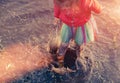 Crop girl playing in muddy puddle