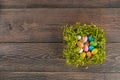 Colorful easter eggs in green nest on table.