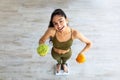 Above view of happy Indian lady holding citrus fruit and cabbage, standing on scales, choosing healthy diet, full length Royalty Free Stock Photo