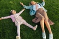 Above view image of happy mom lying on the green grass with her cute little girl in the park. Cheerful young woman relaxing with Royalty Free Stock Photo
